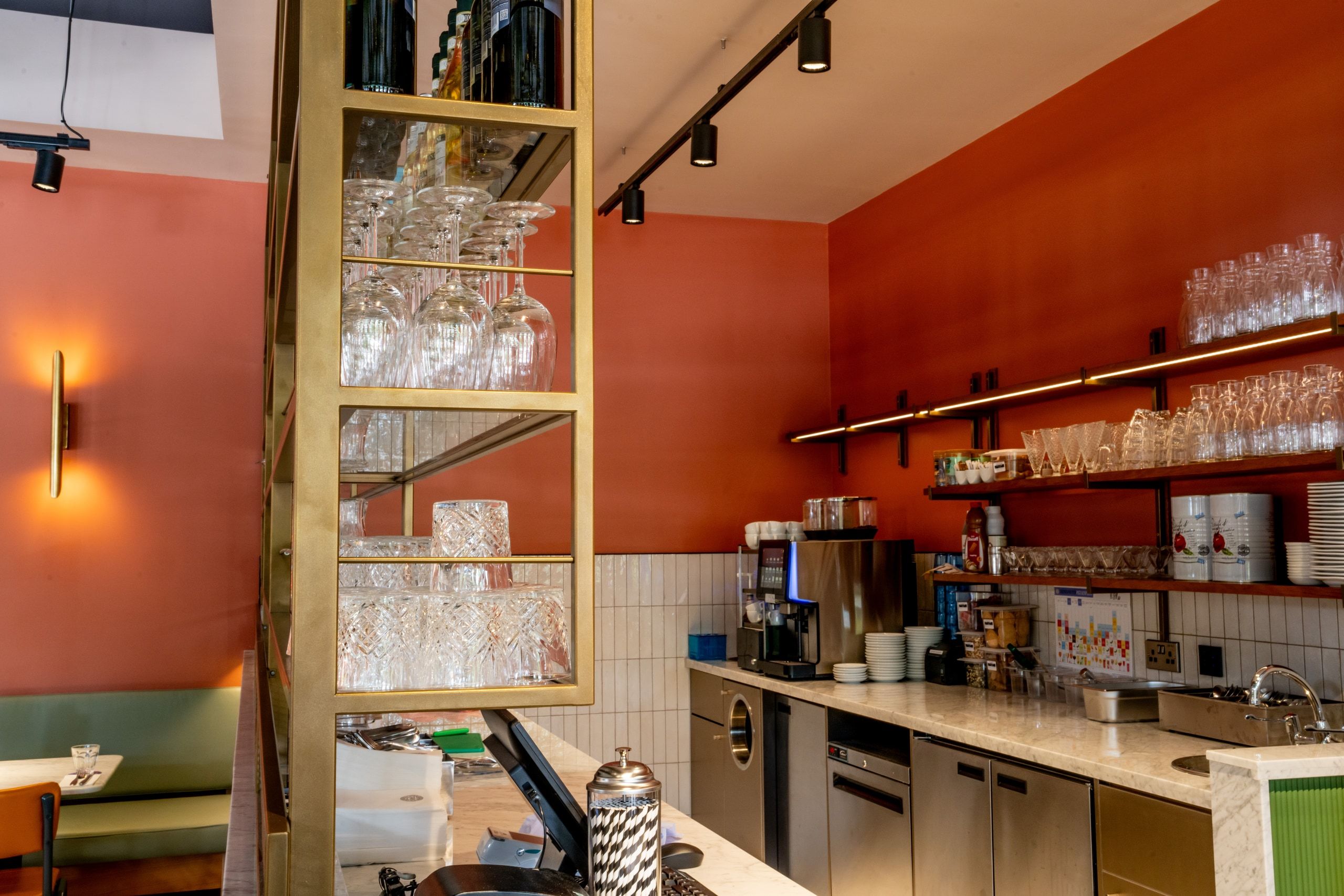 The finished dessert bar, with brass shelving, glassware and a stainless servery counter.