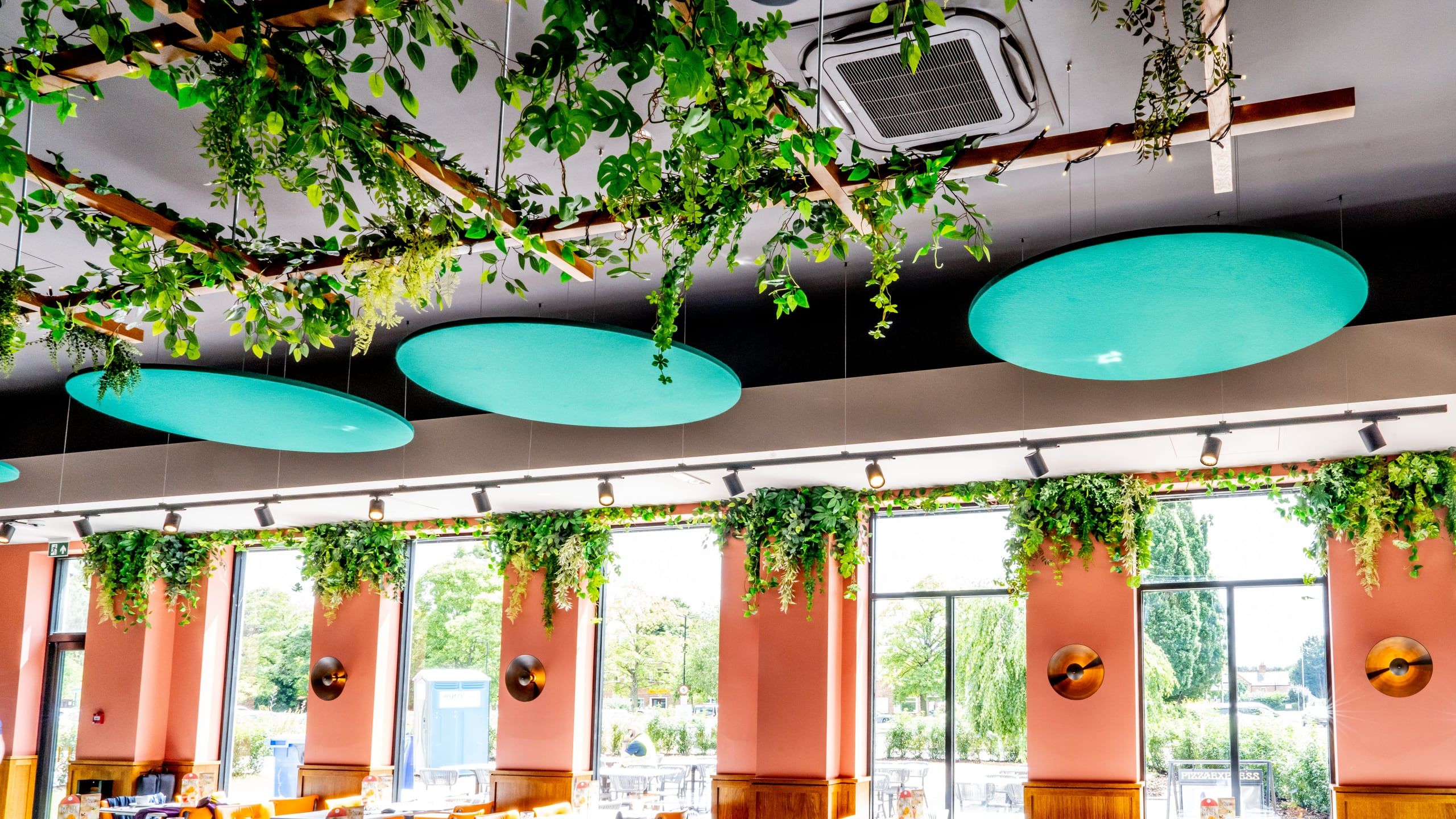 A bright, finished Pizza Express dining room with hanging greenery, fitted out by AB Group.