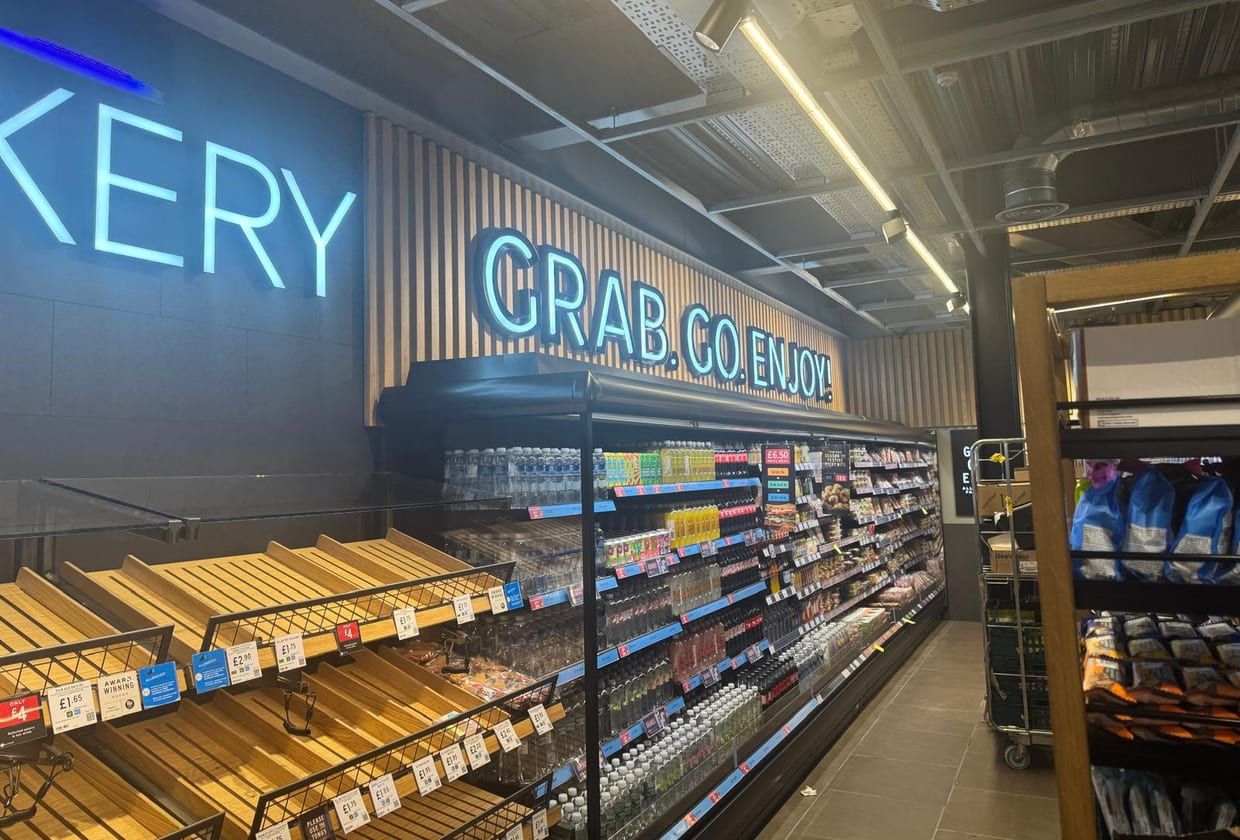 A finished grab-and-go aisle lit in blue neon, with chilled cabinets.