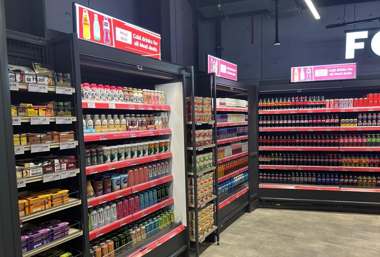 A stocked run of chilled and ambient shelving in a finished convenience store.