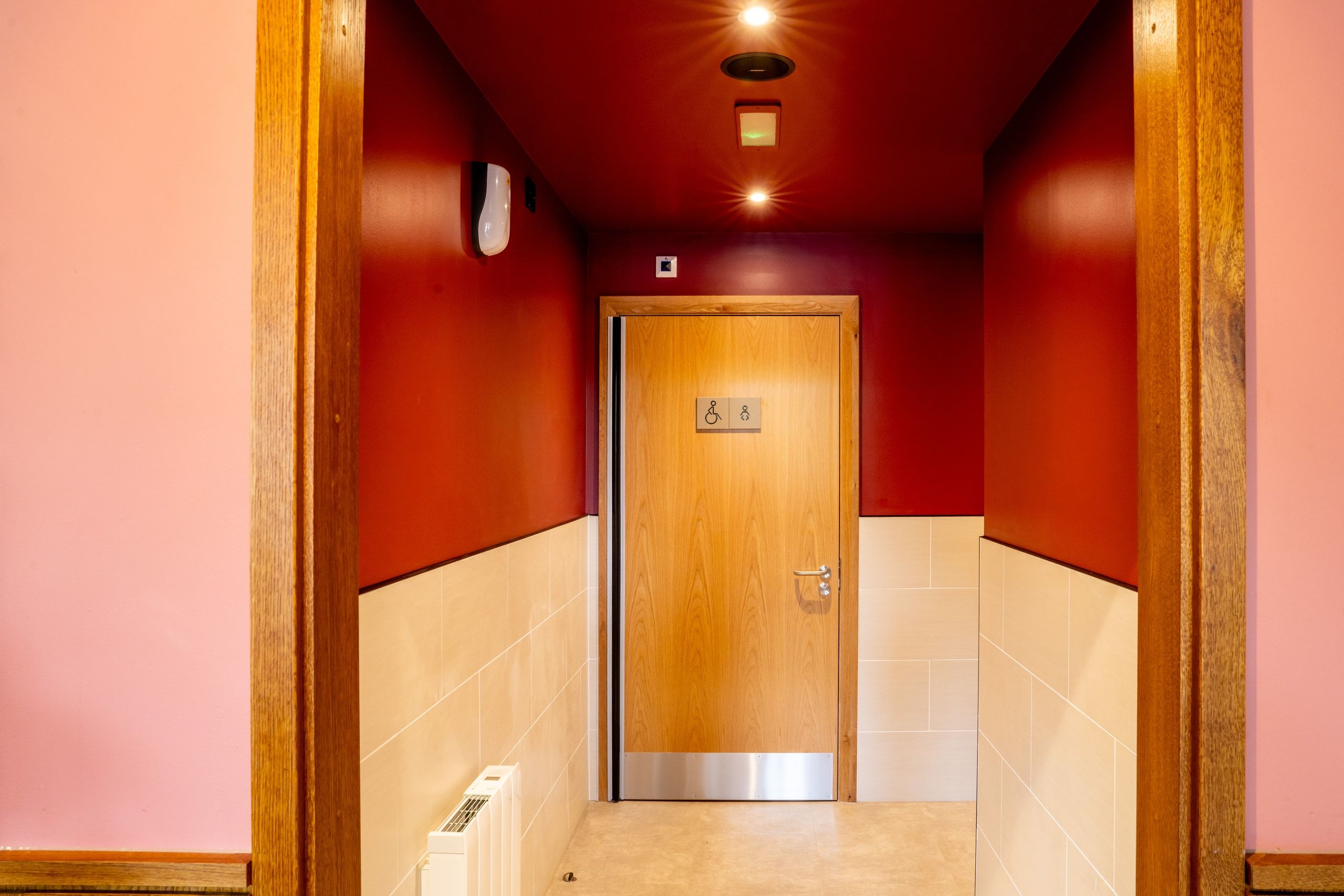 The finished public toilet lobby, with tiled walls and an accessible WC door.